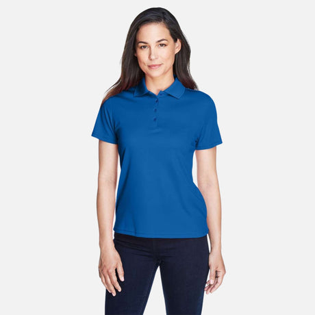 Polo femme Core365 performance Origin en tissu bleu royal, col classique et logo brodé, vêtement sport élégant.